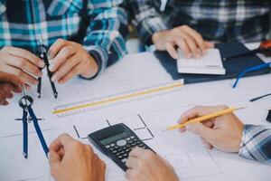 engineer people meeting working and pointing at a drawings in office for discussing. Engineering tools and construction concept. photo