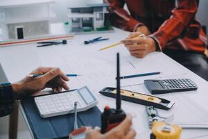 engineer people meeting working and pointing at a drawings in office for discussing. Engineering tools and construction concept. photo