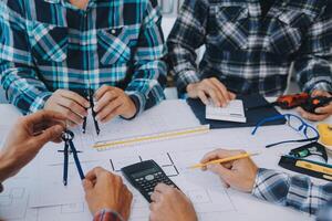 engineer people meeting working and pointing at a drawings in office for discussing. Engineering tools and construction concept. photo