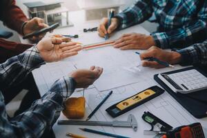 engineer people meeting working and pointing at a drawings in office for discussing. Engineering tools and construction concept. photo
