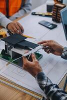 imagen de ingeniero reunión para arquitectónico proyecto. trabajando con compañero y Ingenieria herramientas en lugar de trabajo Clásico tono. foto