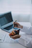 Doctor explaining heart to elderly patient. Doctor explaining the heart model. Doctors pen point to a model of the heart photo