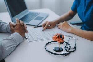 Doctor explaining brain functions to patient on model in office. photo