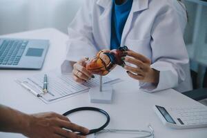 Doctor explaining heart to elderly patient. Doctor explaining the heart model. Doctors pen point to a model of the heart photo