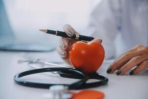 Doctor explaining heart to elderly patient. Doctor explaining the heart model. Doctors pen point to a model of the heart photo