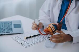 Doctor explaining heart to elderly patient. Doctor explaining the heart model. Doctors pen point to a model of the heart photo