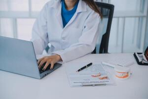 los dentistas están discutiendo problemas dentales al informar la imagen de rayos X en la pantalla del portátil a los pacientes. foto