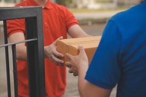 Asian delivery express courier young man use giving boxes to woman customer he wearing protective face mask at front home photo