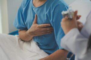 joven médico es utilizando un estetoscopio escucha a el latido del corazón de el paciente. Disparo de un hembra médico dando un masculino paciente un cheque arriba foto