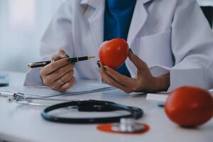 Doctor explaining heart to elderly patient. Doctor explaining the heart model. Doctors pen point to a model of the heart photo