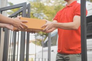 Asian delivery express courier young man use giving boxes to woman customer he wearing protective face mask at front home photo