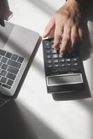 hombre de negocios que trabaja en la oficina de escritorio usando una calculadora para calcular los números, el concepto de contabilidad financiera foto
