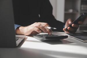 hombre de negocios que trabaja en la oficina de escritorio usando una calculadora para calcular los números, el concepto de contabilidad financiera foto