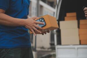 asiático entrega Rápido mensajero joven hombre utilizar dando cajas a mujer cliente él vistiendo protector cara máscara a frente hogar foto