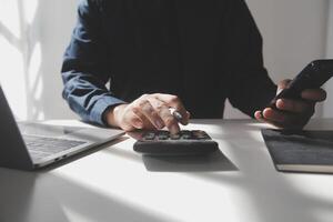 hombre de negocios que trabaja en la oficina de escritorio usando una calculadora para calcular los números, el concepto de contabilidad financiera foto