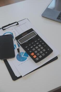 Close up view of simple workspace with laptop, notebooks, coffee cup and tree pot on white table with blurred office room background photo
