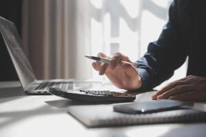 hombre de negocios que trabaja en la oficina de escritorio usando una calculadora para calcular los números, el concepto de contabilidad financiera foto