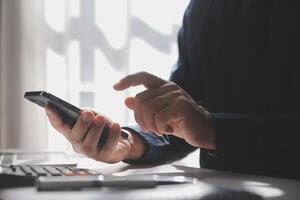 Side view shot of a man's hands using smart phone in interior, rear view of business man hands busy using cell phone at office desk, young male student typing on phone sitting at wooden table, flare photo