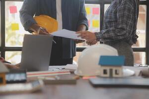 A team of construction engineers talks to managers and construction workers at the construction site. Quality inspection, work plan, home and industrial building design project photo