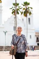 Senior adult woman at the central square in the city of Guaduas located in the Department of Cundinamarca in Colombia. Senior lifestyle. Senior travel concept. photo