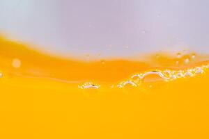 Close up bright orange juice splash texture for health and nature waves, Beautiful waves curve and little bubbles smooth for garphic design and background photo