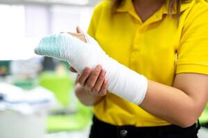 Woman's hand wrapped in white bandage from accident, injury, accident insurance, soft splint on finger, copy space photo