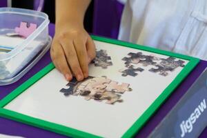 Thai students create jigsaw puzzles of important scientists in the science learning base on Thailand's National Science Day. Soft and selective focus. photo