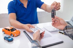 car dealer is handing over car keys to customer after sales contract and installment contract have been signed. Concept of handing over car keys to customers after the sales contract has been approved photo