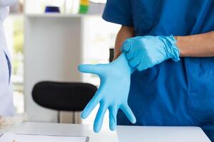 doctor is wearing blue rubber gloves prevent direct contact with patient because virus may be traced to patient body and medical rubber gloves also help prevent virus from being transmitted to patient photo