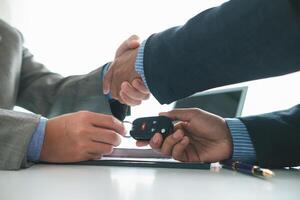 customer and car dealer shake hands after agreeing to sales contract before making contract payment and handing over car keys to customer. concept of handshake between customers and car dealers. photo