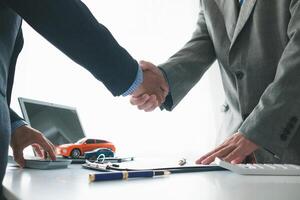 customer and car dealer shake hands after agreeing to sales contract before making contract payment and handing over car keys to customer. concept of handshake between customers and car dealers. photo