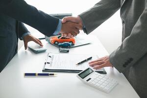 customer and car dealer shake hands after agreeing to sales contract before making contract payment and handing over car keys to customer. concept of handshake between customers and car dealers. photo