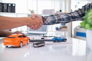 cliente y coche comerciante sacudir manos después estar de acuerdo a ventas contrato antes de haciendo contrato pago y entrega terminado coche llaves a cliente. concepto de apretón de manos Entre clientes y coche distribuidores foto