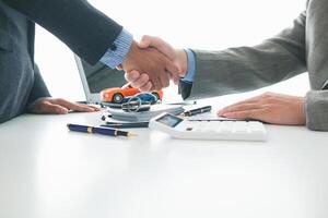 customer and car dealer shake hands after agreeing to sales contract before making contract payment and handing over car keys to customer. concept of handshake between customers and car dealers. photo