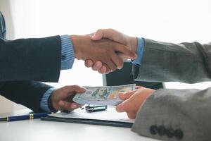 customer and car dealer shake hands after agreeing to sales contract before making contract payment and handing over car keys to customer. concept of handshake between customers and car dealers. photo