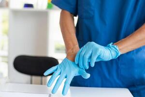 doctor is wearing blue rubber gloves prevent direct contact with patient because virus may be traced to patient body and medical rubber gloves also help prevent virus from being transmitted to patient photo