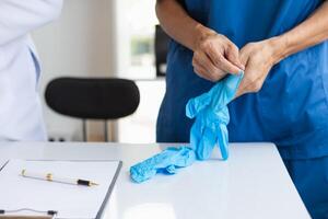 doctor is wearing blue rubber gloves prevent direct contact with patient because virus may be traced to patient body and medical rubber gloves also help prevent virus from being transmitted to patient photo