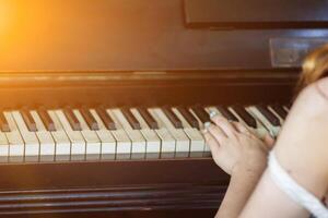 The girl is playing the piano at a party to celebrate the success of the businessman. The piano was set up by the window of the music room in the morning for pianists to practice the piano. photo