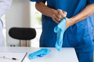 doctor is wearing blue rubber gloves prevent direct contact with patient because virus may be traced to patient body and medical rubber gloves also help prevent virus from being transmitted to patient photo