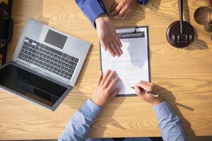 contract was placed on table inside legal counsel's office, ready for investors to sign the contract to hire a team of lawyers to provide legal advice for their investment. legal consulting concept photo