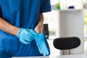 doctor is wearing blue rubber gloves prevent direct contact with patient because virus may be traced to patient body and medical rubber gloves also help prevent virus from being transmitted to patient photo