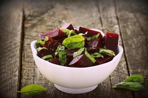 Beetroot chopped for salad with basil and dill seeds in bowl on rustic wooden table photo