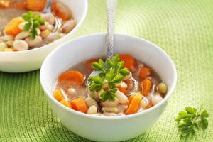 Vegetable soup with bean and carrots on green background photo