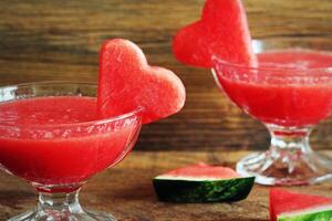 Healthy watermelon smoothie with of watermelon in heart shape on a wood background photo