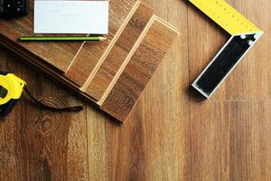 Laminate floor planks and tools on wooden background photo