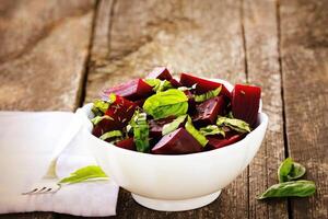 Beetroot chopped for salad with basil and dill seeds in bowl on rustic wooden table photo