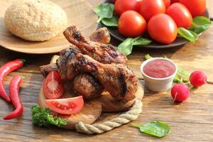 Grilled chicken legs on cutting board.Rustic dinner background. photo