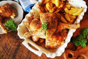 Grilled chicken leg, quarter with potato for garnish. Top view. Wooden background photo