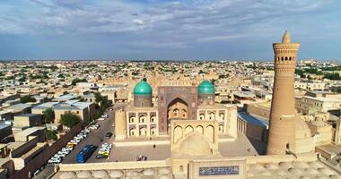 un' fuco mosche al di sopra di il Torre di un antico complesso kalyan minareto su un' soleggiato, nuvoloso giorno. vecchio Buchara, Uzbekistan. video