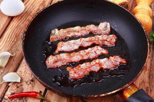 Fried bacon in a frying pan photo